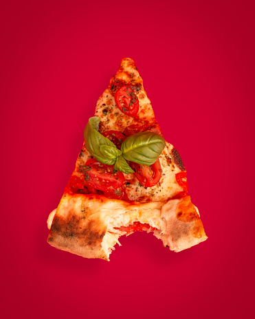 A vertical shot of a slice of pizza with tomato and basil