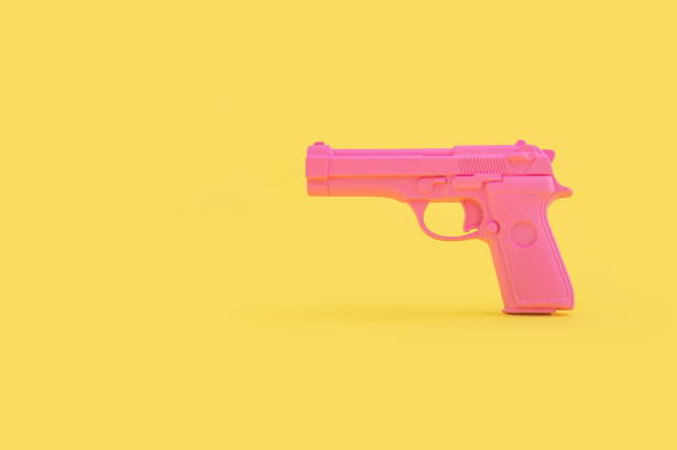 giocattolo di pistola rosa isolato su uno sfondo giallo brillante con uno spazio di copia - toy gun foto e immagini stock