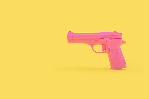 A pink gun toy isolated on a bright yellow background with a copy space
