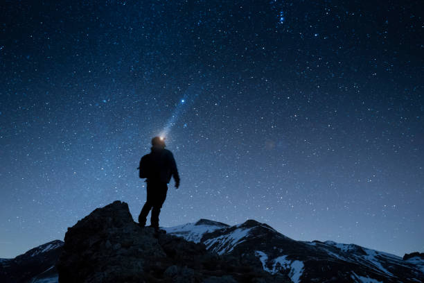istock man looking to the night sky in the mountains 1463404626
