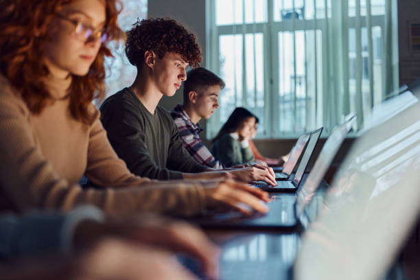 High school students e-learning over computers in the classroom. Group of high school students studying over laptops on a class at school. computer lab stock pictures, royalty-free photos & images