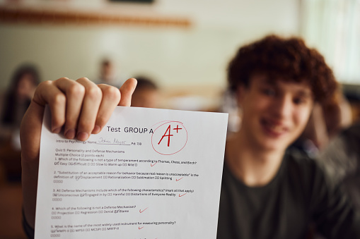 Close up of a male student showing his A grade on a test at high school.