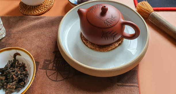 teezeremonie. chinesische pu-erh in einer schüssel. im hintergrund ist eine braune teekanne und teeblätter. - italian dessert audio stock-fotos und bilder