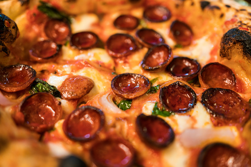 Neapolitan pizza style: close-up chorizo sausage pizza. Ingredients such as chorizo sausage, mozzarella cheese, sliced radish and olive oil. Focus on chorizo. Italian freshly baked Napoli pizza.