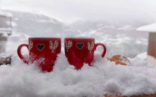 istock two red mugs with heart shaped on the snow and mountain background 1463412810