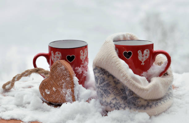 istock two red mugs with heart shaped one in a woolen hat  on the snow 1463413012