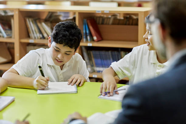 istock Schoolboys working at round table with male educator 1463413140