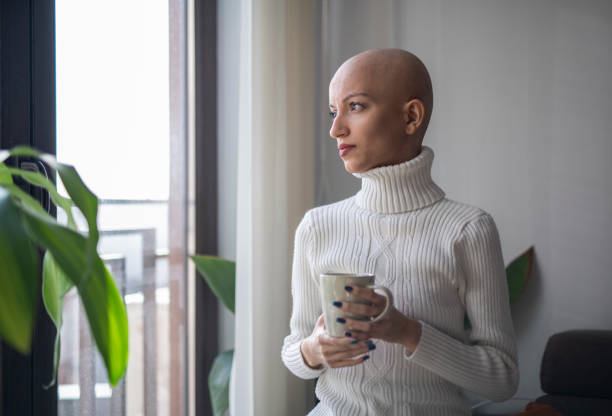 istock Young cancer patient looking through window with a cup of tea in hands. 1463413408