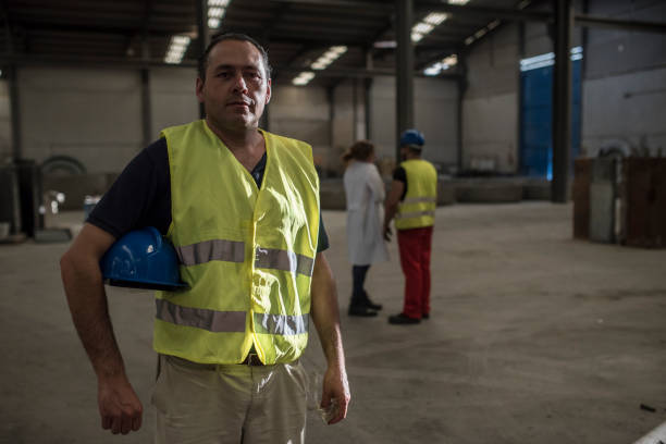 istock construction worker poses in dramatic lighting looking at the camera with his coworkers in the background (man and pregnant woman) 1463413760