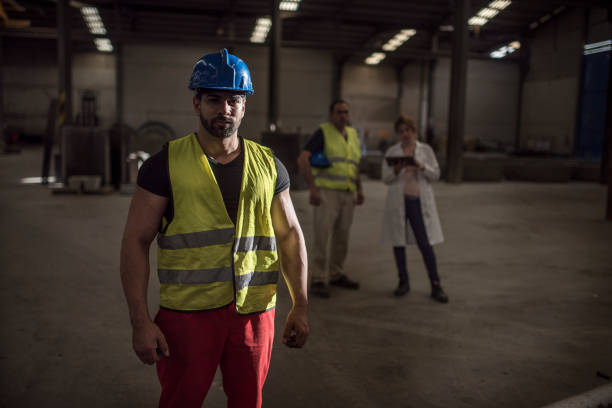 istock construction worker poses in dramatic lighting looking at the camera with his coworkers in the background (man and pregnant lab woman) 1463413765