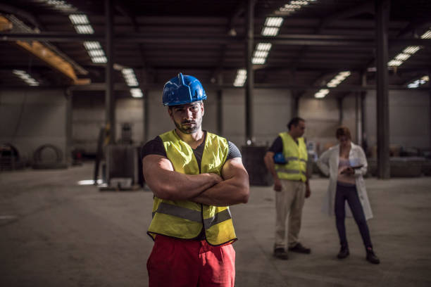 istock construction worker poses in dramatic lighting looking at the camera with his coworkers in the background (man and pregnant lab woman) 1463413774