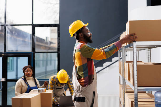 istock Warehouse worker in hard hat taking carton from shelf 1463414641