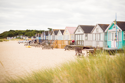 Row of wooden beach huts between sand dunes. Hengistbury Head, Dorset, UK