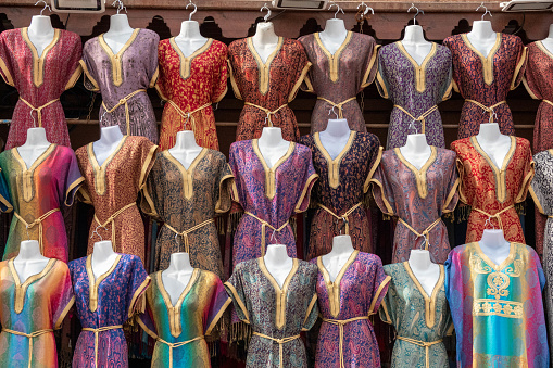Close-up of a large group of colorful dresses displayed in a market stall. The photo was taken in the medina (an ancient, historic market) in Marrakech, Morocco