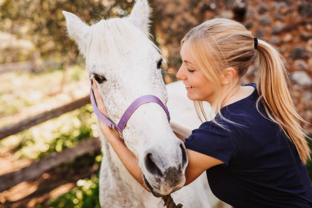 istock Smiling young blond woman cuddling with her white horse 1463420708