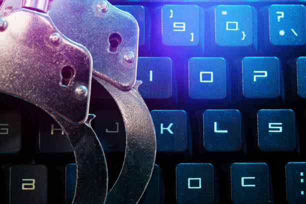 Metal handcuffs on computer keyboard, internet cybercrime concept
