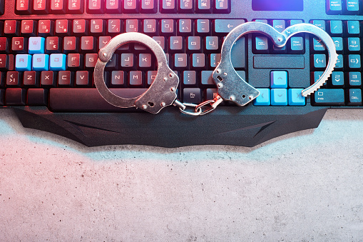 Metal handcuffs on computer keyboard, censored journalism, social media censorship concept. Being stuck in a demanding or boring job