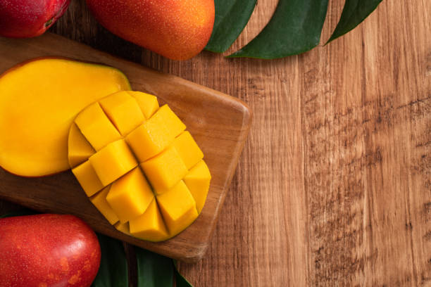 istock Fresh mango fruit with leaves over dark wooden table background. 1463428776