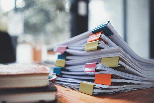 las pilas de documentos que yacen sobre el escritorio están esperando ser verificadas antes de ser enviadas a la junta directiva para utilizar la información correcta antes de reunirse con empresarios e inversores. - burocracia fotografías e imágenes de stock
