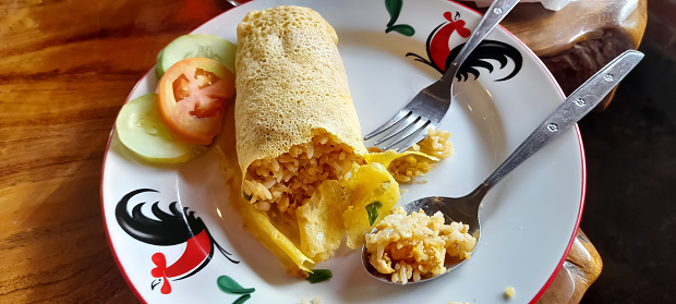 breakfast with fried rice wrapped in an omelet and vegetables