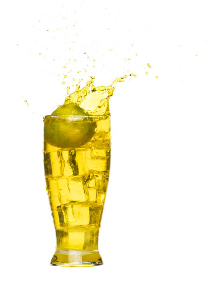 Splash spill lime juice down in ice cube glass, lime juice fall down in yellow liquid water. Green lime in juice throw splash in air. White background Isolated high speed shutter, freeze action