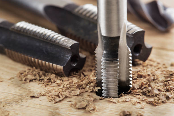 istock Thread tap drill cutting hole in wooden plate. Working cutter. 1463440535