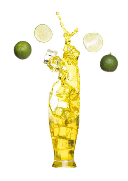istock Splash spill lime juice down in ice cube glass, lime juice fall down in yellow liquid water. Green lime in juice throw splash in air. White background Isolated high speed shutter, freeze action 1463440762