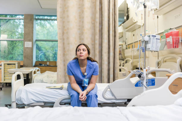 Nurse sits on hospital bed to take a break stock photo