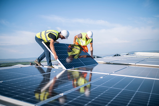 Two workers on a rooftop installing a photovoltaic system.