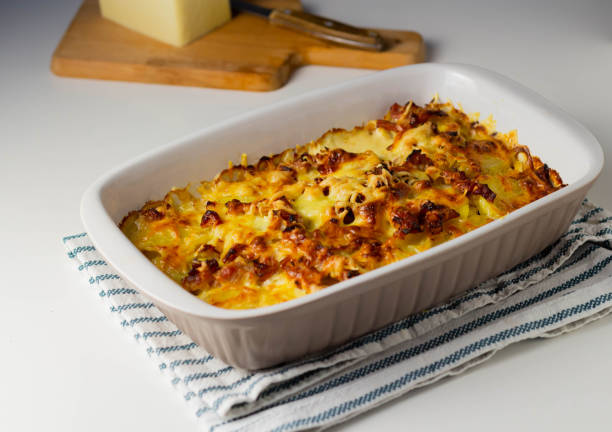 istock Potato casserole with cheese in ceramic form on a napkin on a white table. 1463443674