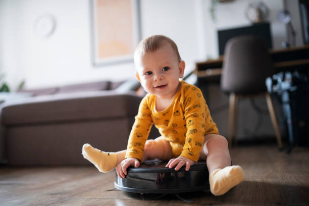 istock Cute baby boy sitting on the robot vacuum cleaner. 1463445547
