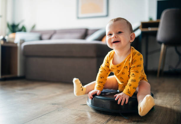 istock Cute baby boy is riding on a robot vacuum. 1463445549