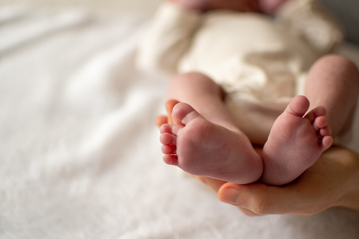 Close-up view of a baby feet holded by her mom. Copyspace