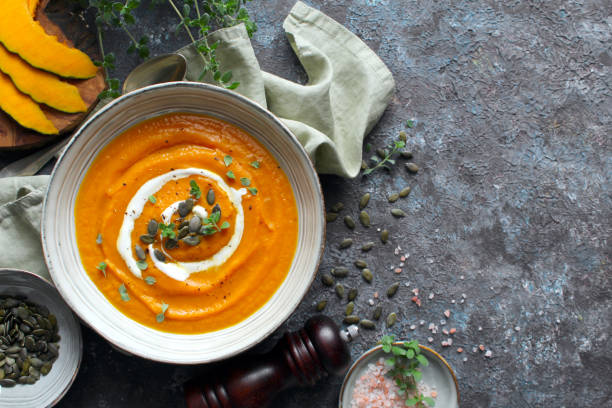 Pumpkin and carrot soup served with cream and pumpkin seeds. stock photo