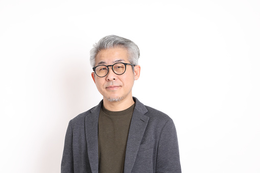 The senior Asian man with grey hair standing on the white background.