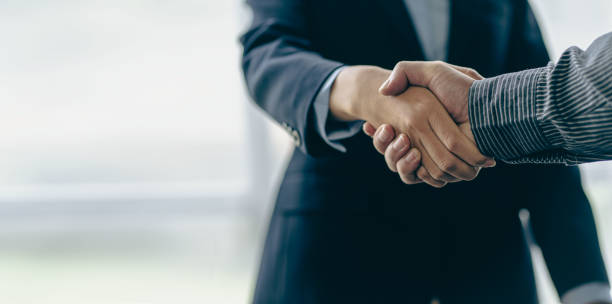 Successful negotiation and handshake concept Two businessmen shake hands with partners to celebrate cooperation and teamwork, mergers and acquisitions. Successful negotiations, business deal concept stock photo