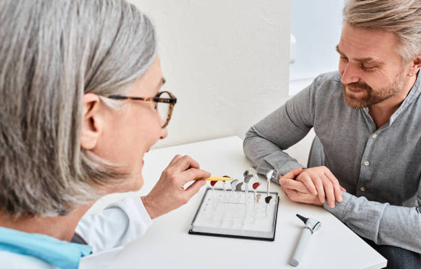 Female audiologist offers BTE hearing aids to man patient with hearing problems for treatment his deafness. Hearing aid selection Female audiologist offers BTE hearing aids to man patient with hearing problems for treatment his deafness. Hearing aid selection Doctor showing hearing aid stock photo stock pictures, royalty-free photos & images