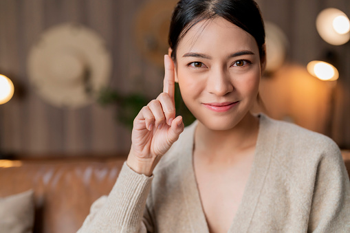 portrait of asian female attractive  woman look at camera hand finger point thoughtful emotion facial face expression at home