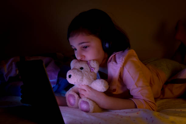 istock Little girl using digital tablet in her bed at night 1463461896