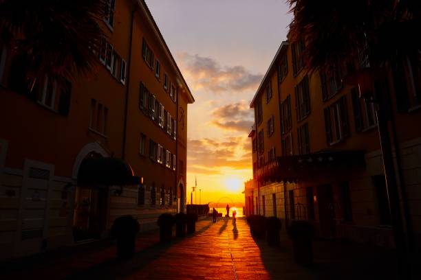 The city of Sirmione in northern Italy at sunset. Sunset in the city of Sirmione. The setting sun makes its way into the narrow streets of Sirmione on the shores of Lake Garda. sirmione es un municipio situado en el territorio de la provincia de brescia, (italia). limita con lombardía y peschiera del garda en la provincia de verona y la región del véneto. tiene un centro histórico que se encuentra en la parte inferior del lag