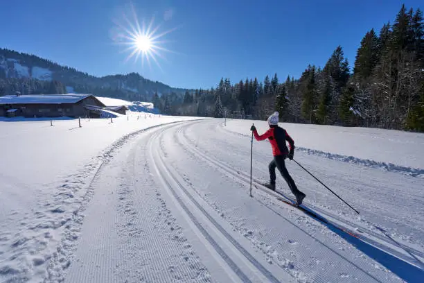 beautiful active senior woman cross-country skiing in fresh fallen powder snow in the Allgau alps near Balderschwang, Bavaria, Germany