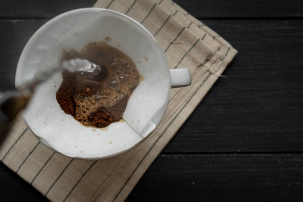 istock Brewed coffee, pouring hot water on ground coffee in a filter on a mug for a stimulating drink, rustic wooden table 1463462518
