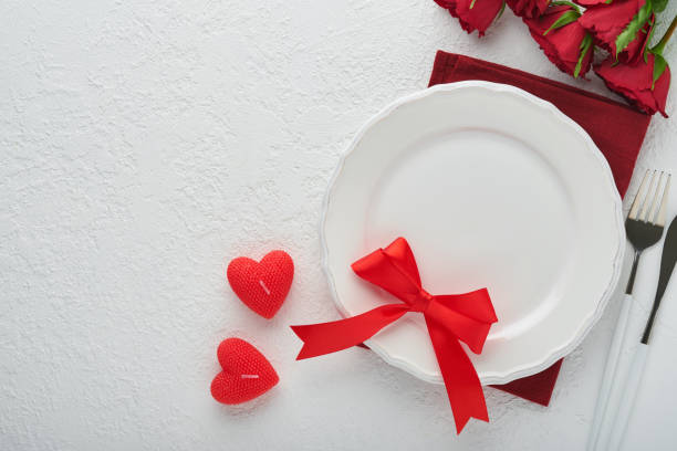 istock Valentines day romantic table setting. Empty or closeup of a dinner black plate, knife, fork and decorative silk hearts on white background. Holiday concept. Copy space for inscriptions. 1463463139