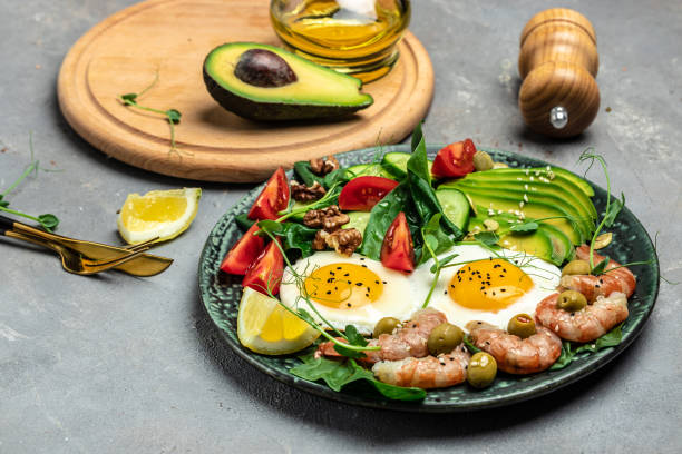 istock shrimps, prawns, soft fried egg, fresh salad, tomatoes, cucumbers and avocado on a light background. Ketogenic diet breakfast. Keto, paleo lunch. Top view 1463463262