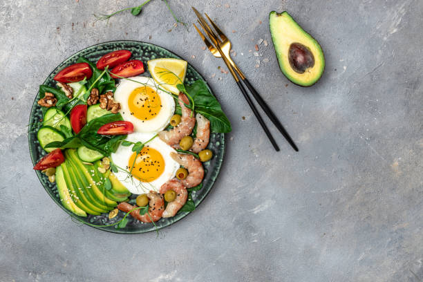 istock shrimps, prawns, soft fried egg, fresh salad, tomatoes, cucumbers and avocado on a light background. Ketogenic diet breakfast. Keto, paleo lunch. Top view 1463463267