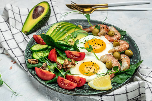 istock shrimps, prawns, soft fried egg, fresh salad, tomatoes, cucumbers and avocado on a light background. Ketogenic diet breakfast. Keto, paleo lunch. Top view 1463463292
