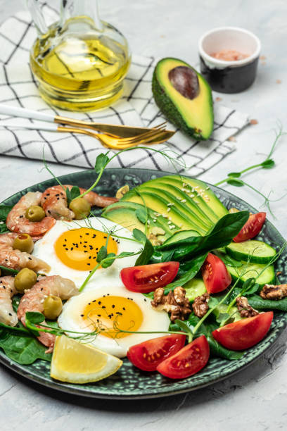 istock Ketogenic diet breakfast shrimps, prawns, soft fried egg, fresh salad, tomatoes, cucumbers and avocado on a dark background. Keto, paleo lunch. vertical image. top view 1463463293
