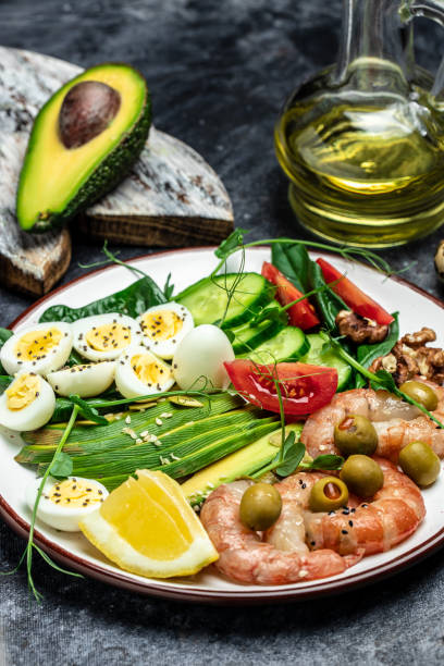 istock shrimps, prawns, soft fried egg, fresh salad, tomatoes, cucumbers and avocado on a light background. Ketogenic diet breakfast. Keto, paleo lunch. Top view 1463463343