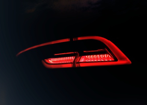 Rear red car LED lights in the dark. Bright modern car headlights on a black background. Background bright red LED car taillights in the dark. Diode stop light.