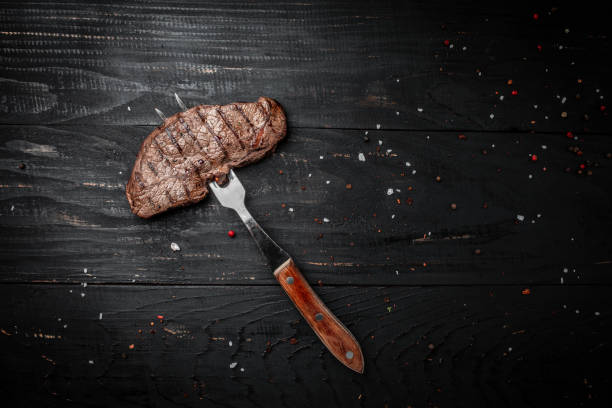 istock Rump Steak on fork on dark wooden background. banner, menu recipe place for text, top view 1463465498